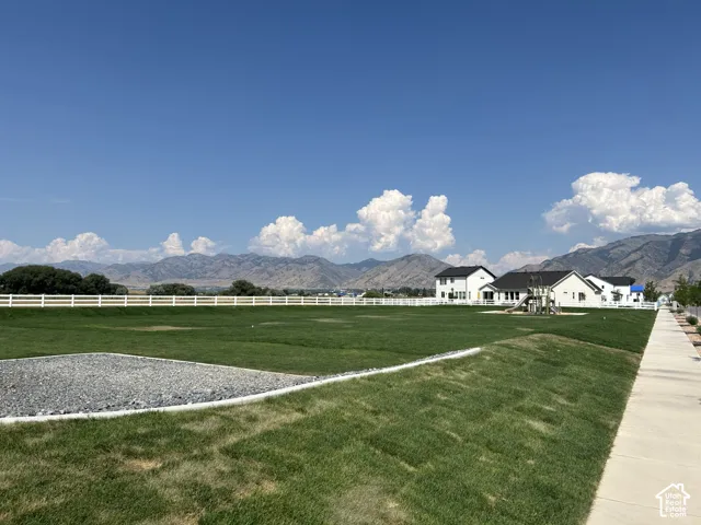 Expansive green space featuring a white perimeter fence and a defined gravel area