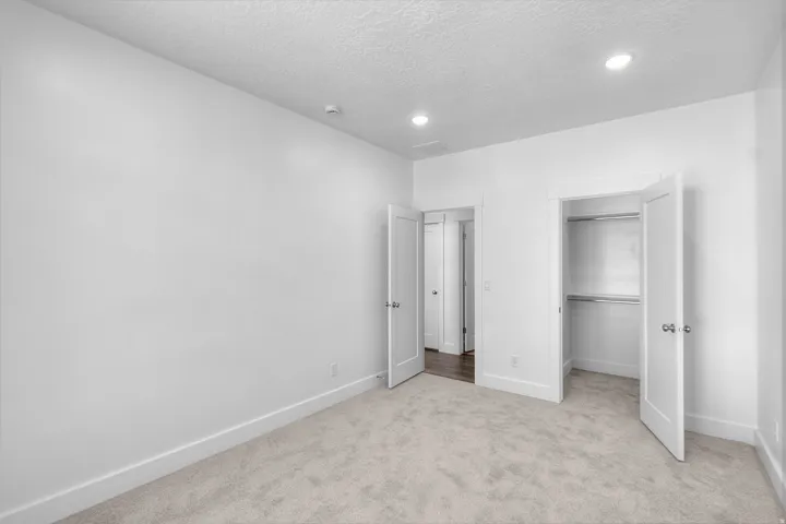 Carpeted bedroom with recessed lighting, white walls, and white trim