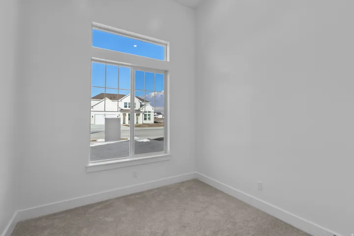 Bright interior space featuring a large window with transom, white trim, light-colored walls, and neutral carpeting