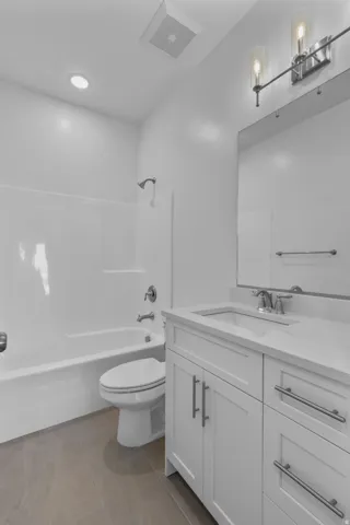 Bathroom vanity featuring a quartz countertop, integrated sink, and white shaker-style cabinetry with brushed nickel hardware