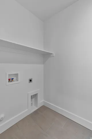 Dedicated laundry area featuring a built-in shelf, appliance hookups, and tiled flooring