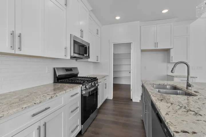 Kitchen featuring white shaker cabinetry, stainless steel appliances, speckled stone countertops, and a subway tile backsplash