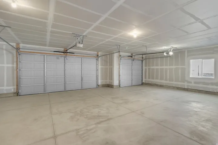 Spacious multi-car garage featuring two overhead doors, concrete flooring, and an integrated window