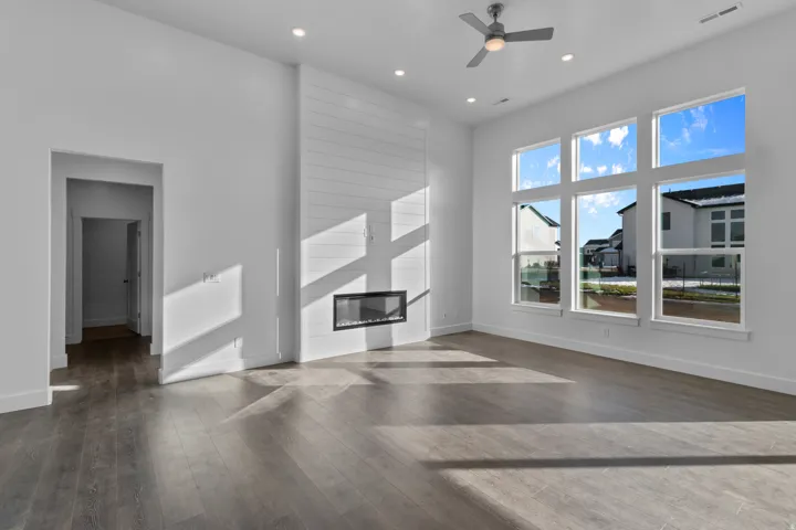 Spacious room featuring high ceilings, wood-finish flooring, and a contemporary linear fireplace set into a shiplap accent wall
