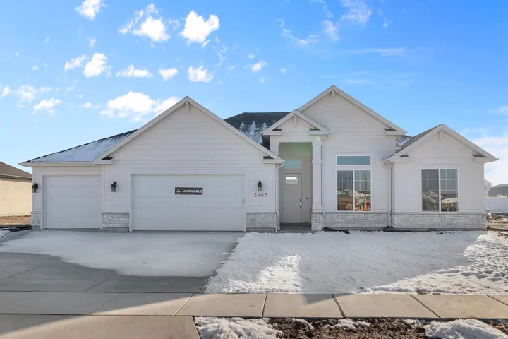 Contemporary exterior featuring white siding, a stone facade accent, a two-car garage, an additional single-car garage, and a covered entry