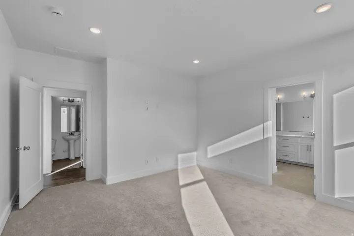 Primary bedroom with light-toned carpeting and recessed ceiling lighting