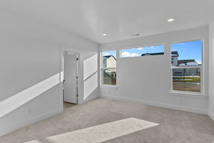 Primary bedroom featuring multiple windows, recessed lighting, neutral carpeting, white trim, and a contemporary door