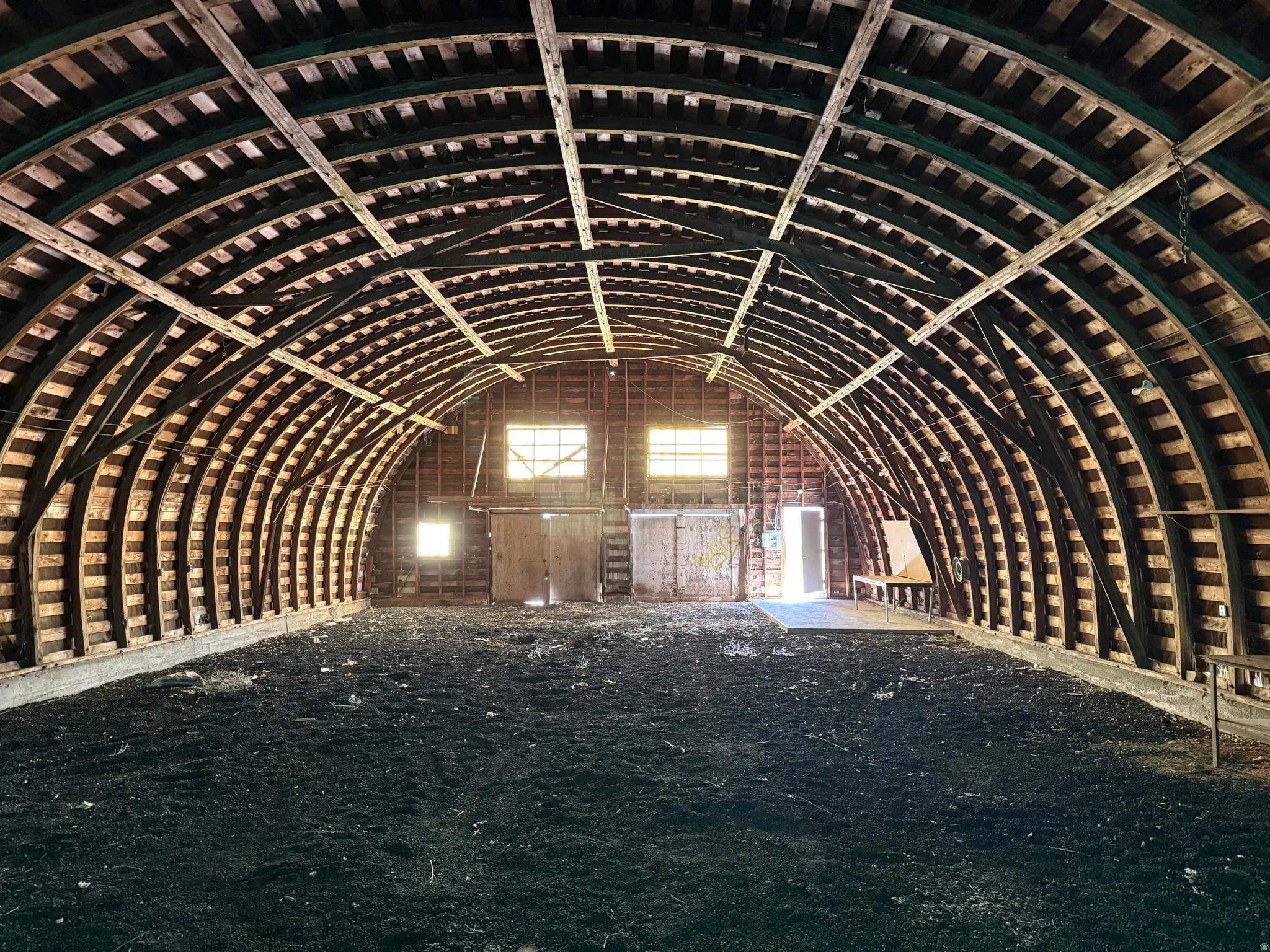 Spacious arched structure featuring exposed wood beam framing, multiple window openings providing ambient light, and a large open floor area