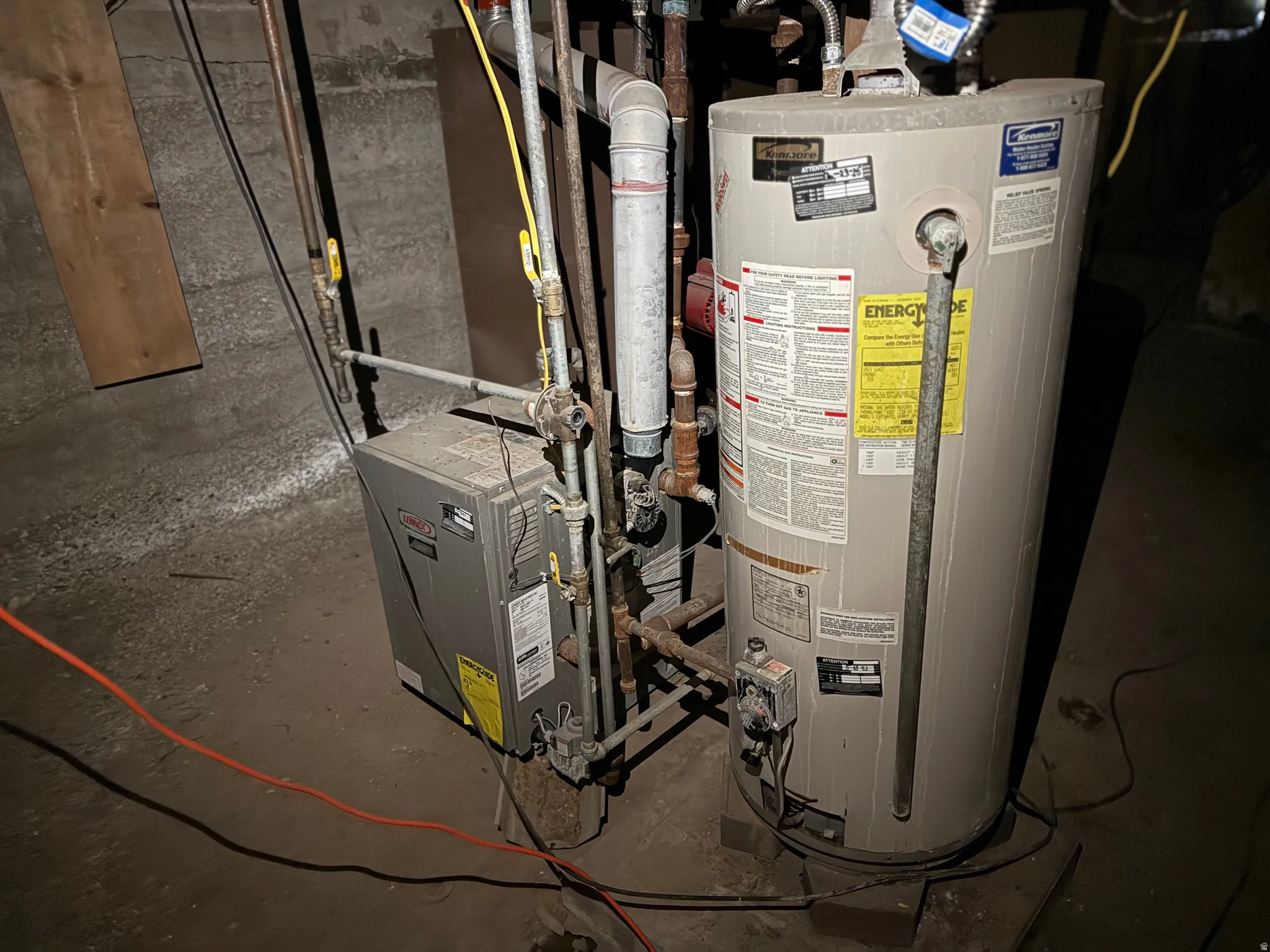 Utility area featuring a water heater and furnace with exposed piping