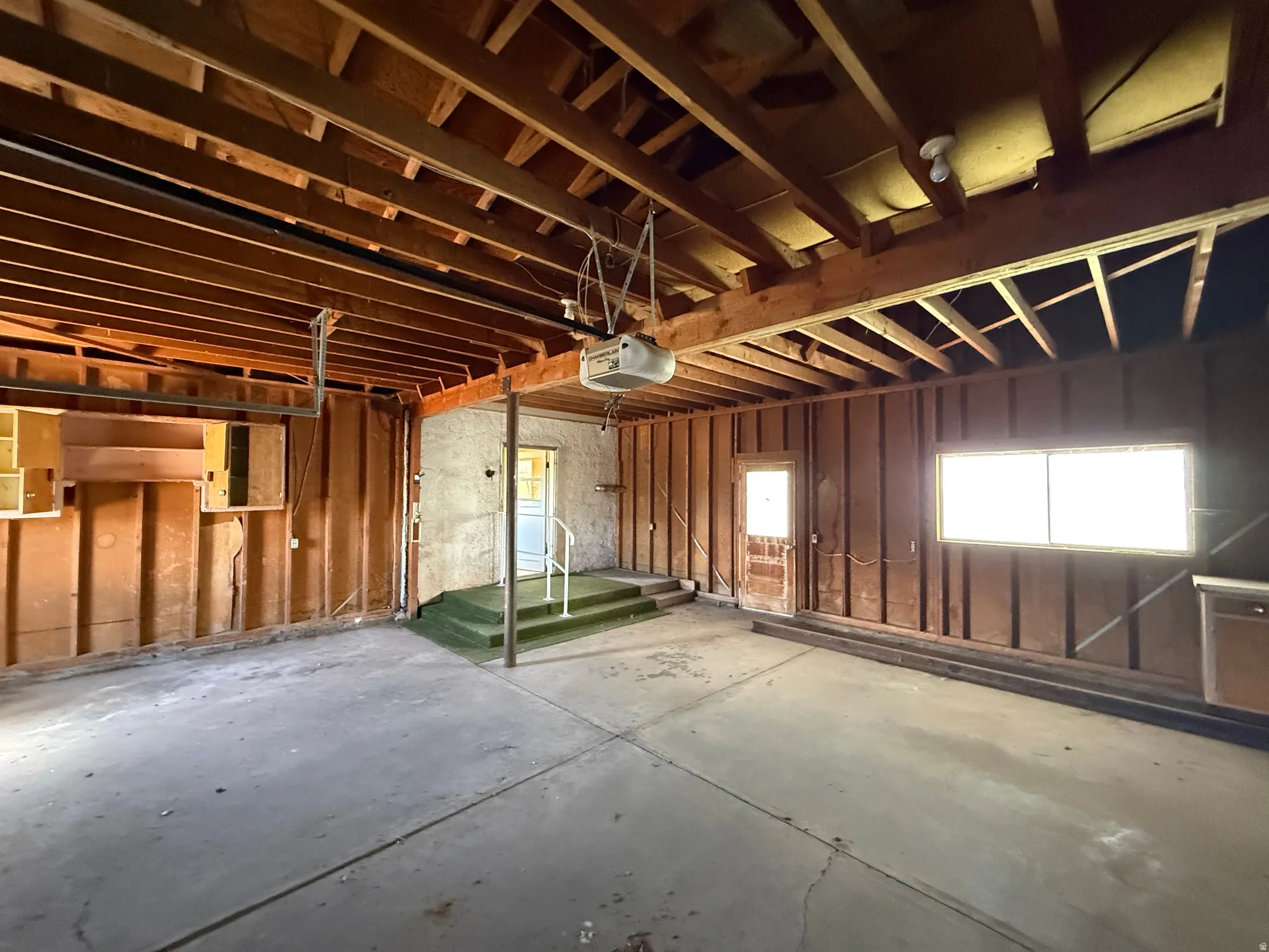 Spacious garage with exposed wood ceiling joists and concrete flooring
