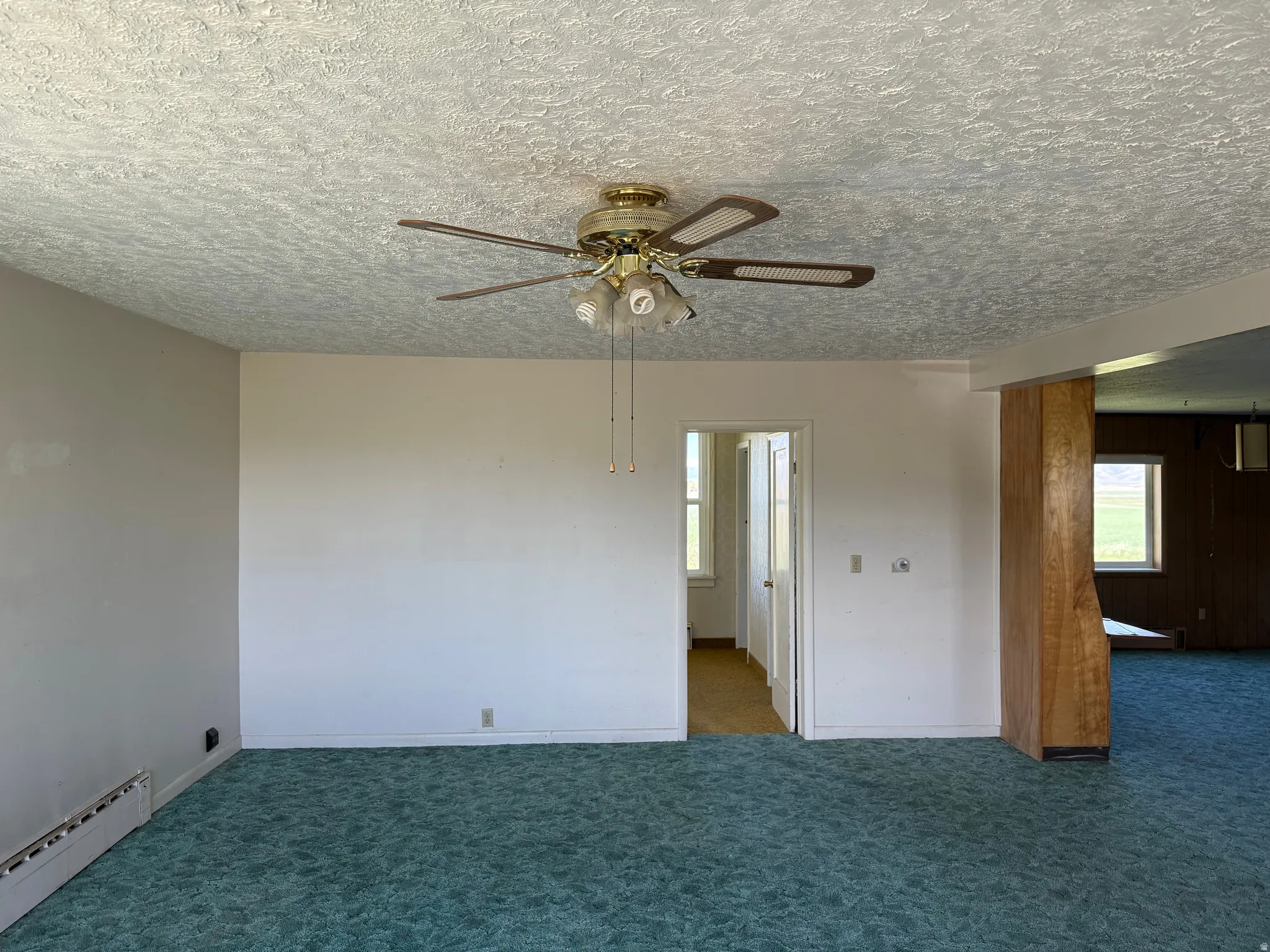 Interior space featuring a textured ceiling with a brass-finish ceiling fan and light fixture