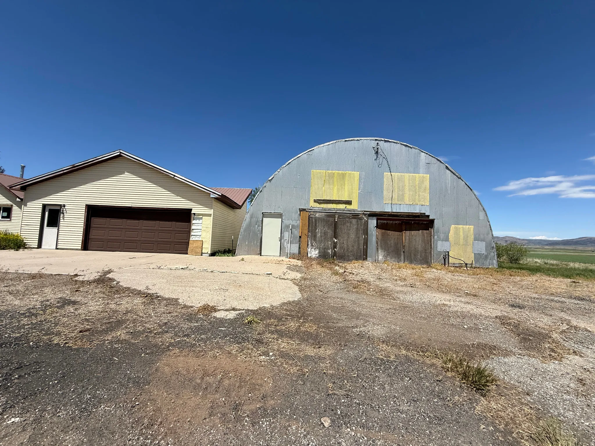 Quonset hut structure featuring a corrugated metal exterior, large double wooden doors, and an additional single entry door