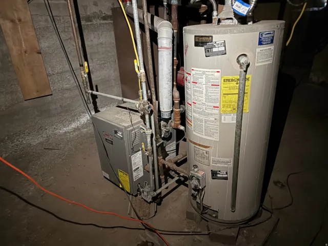 Utility area featuring a water heater and furnace with exposed piping