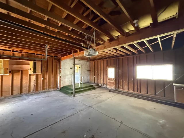 Spacious garage with exposed wood ceiling joists and concrete flooring