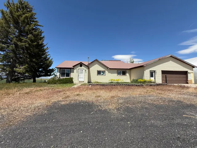 Ranch-style residence featuring a metal roof and an attached garage with a brown door