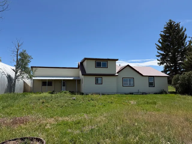 Multi-level residence featuring a light-colored siding and a contrasting reddish-brown metal roof