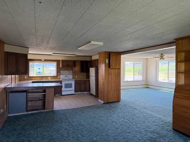 Spacious kitchen with wood-finish cabinetry, white appliances, and a built-in breakfast bar