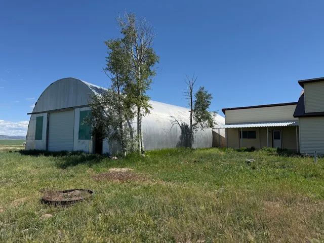Metal quonset-hut style structure with a corrugated metal roof and large roll-up door