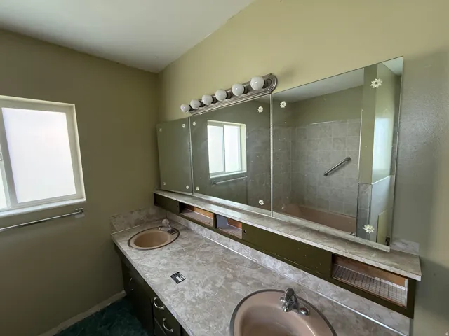 Bathroom featuring a dual vanity with integrated sinks, a three-panel mirrored medicine cabinet, and a five-bulb vanity light fixture