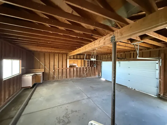 Exposed wood ceiling beams and framing characterize this garage space