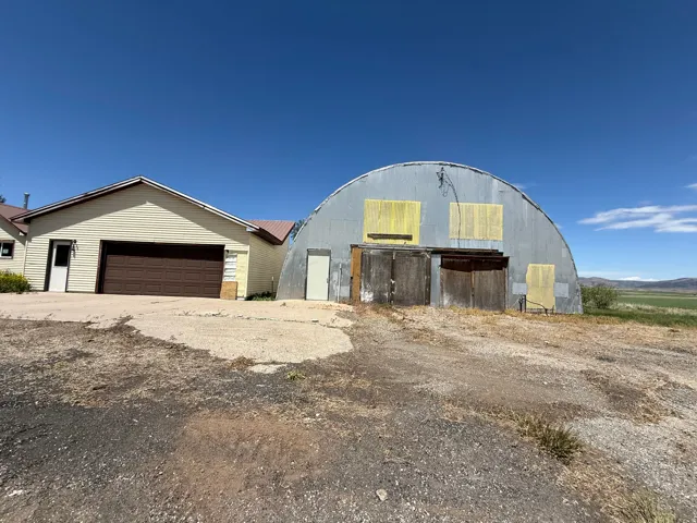 Quonset hut structure featuring a corrugated metal exterior, large double wooden doors, and an additional single entry door