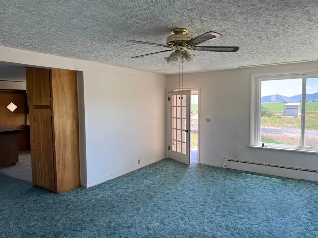Interior space featuring a ceiling fan with light kit, textured ceiling, and light-colored walls