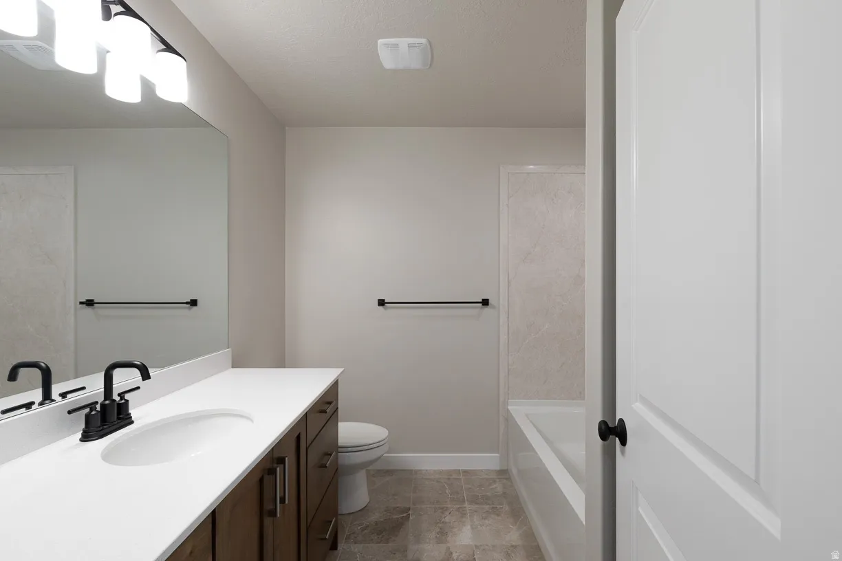 Primary bathroom featuring a long vanity with white countertop, integrated sink, and dark wood-finish cabinetry