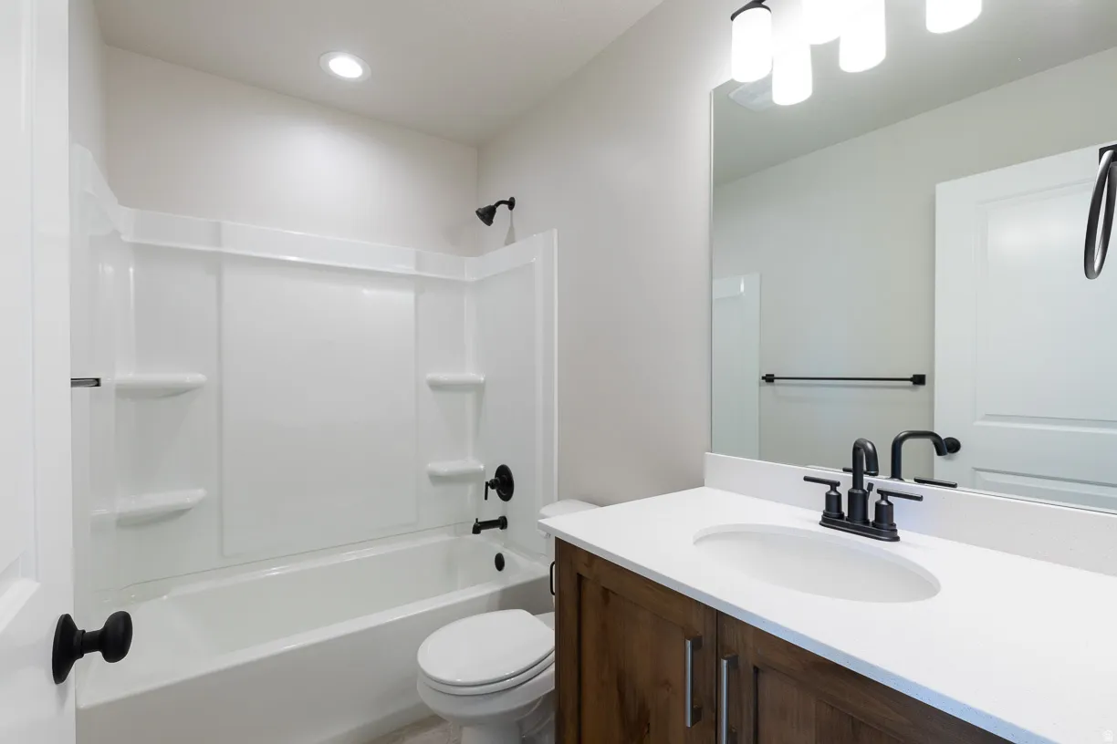 Upstairs common bathroom featuring a wood-finish vanity with a white countertop and undermount sink