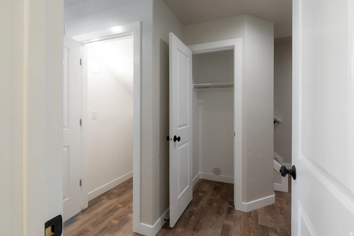 Interior hallway with wood-finish flooring, white doors, and matte black hardware