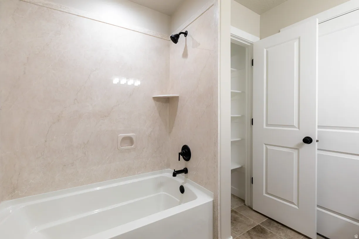 Primary bedroom bathroom has a white soaking tub featuring a black showerhead, black tub faucet, and a wall-mounted soap dish