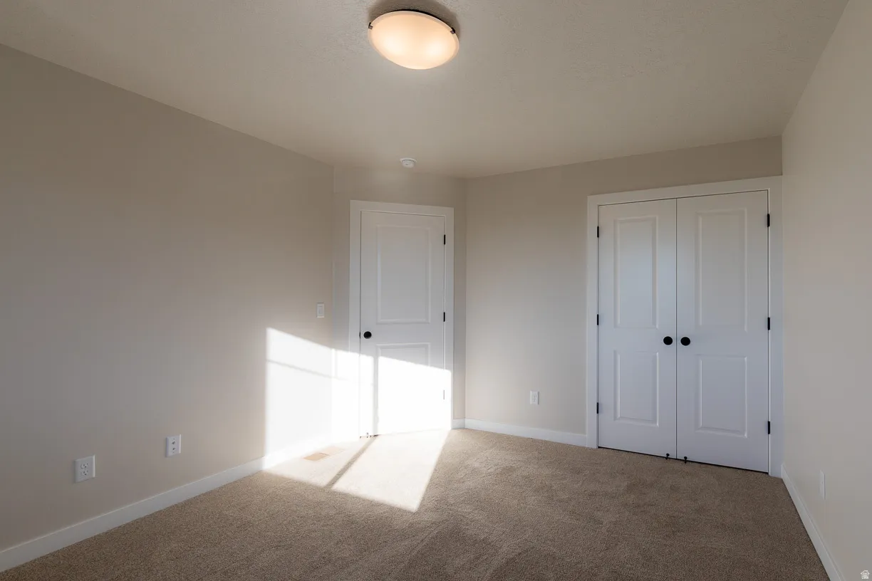 Upstairs bedroom with soft neutral wall color with white trim and closet.