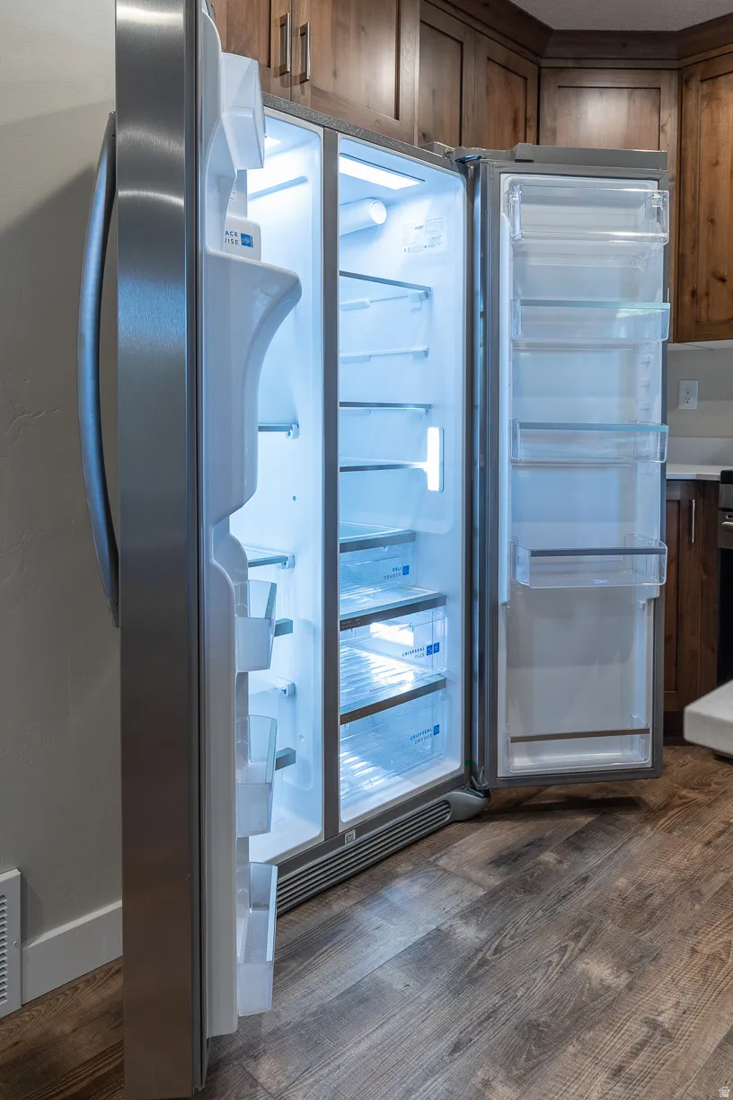 Stainless steel side-by-side refrigerator with interior lighting, clear door bins, and drawer storage
