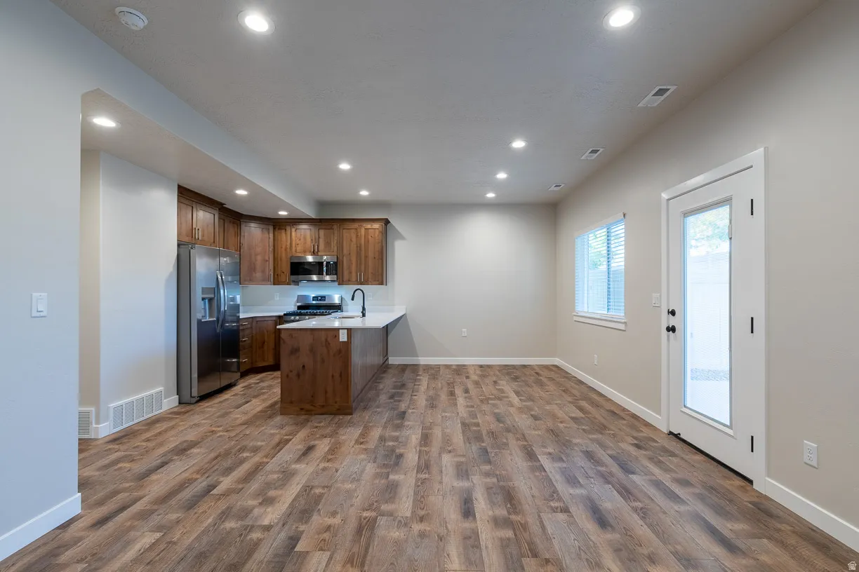 Open-concept living area with wood-finish flooring, a kitchen island, and recessed lighting