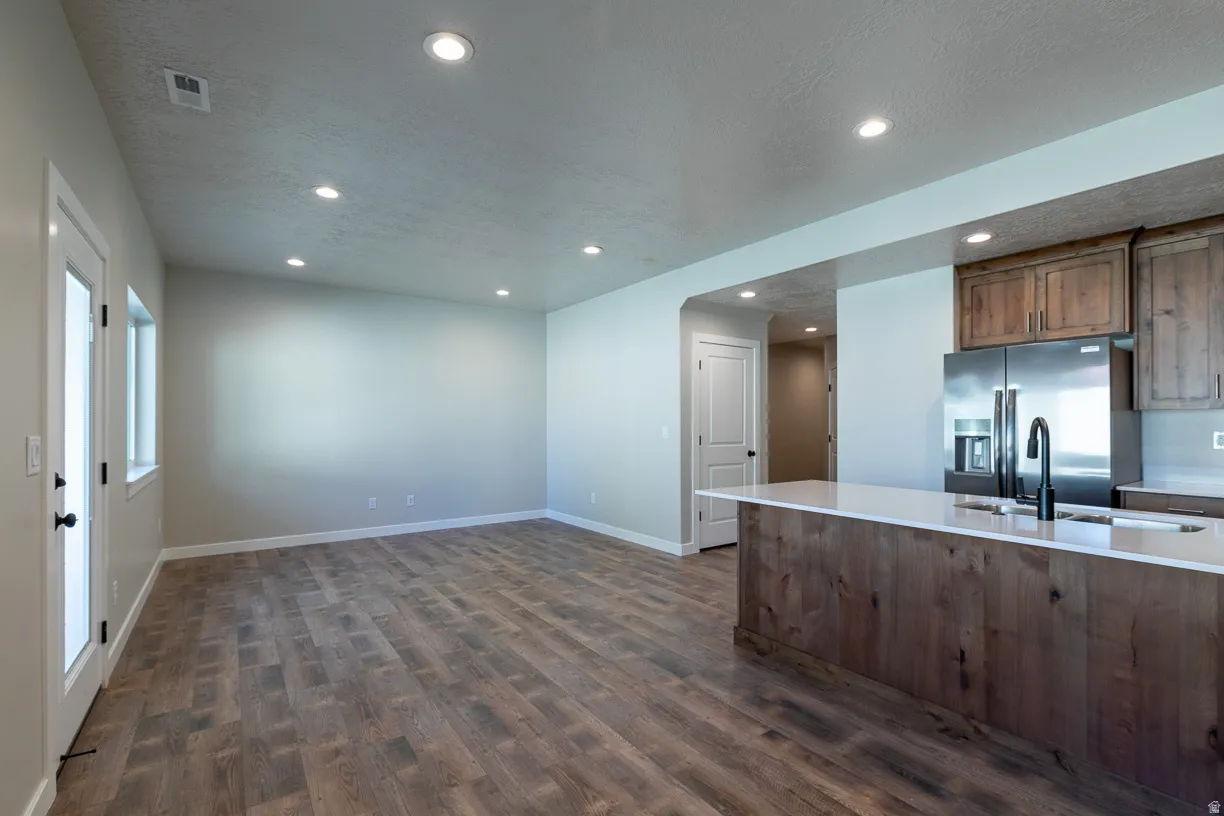 Open-concept room featuring wood-finish flooring, recessed lighting, and a kitchen island with a white countertop