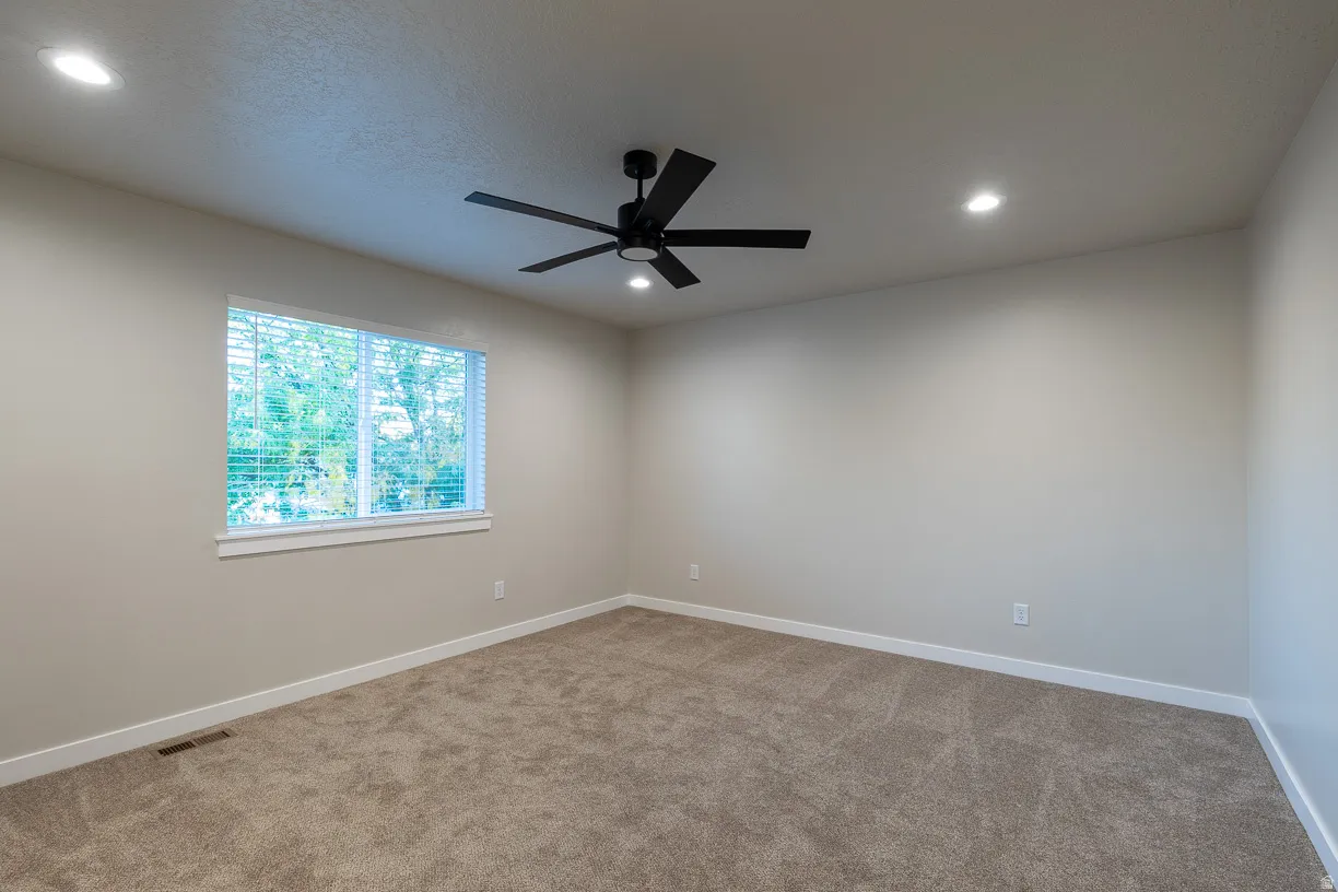 Carpeted room featuring a ceiling fan, recessed lighting, and a window with blinds