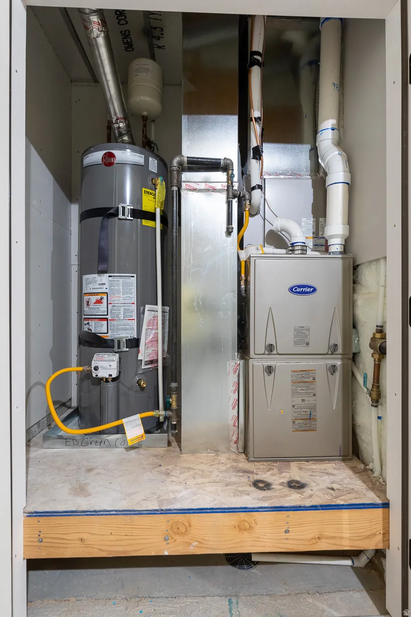 Utility closet featuring a water heater, furnace, and exposed piping
