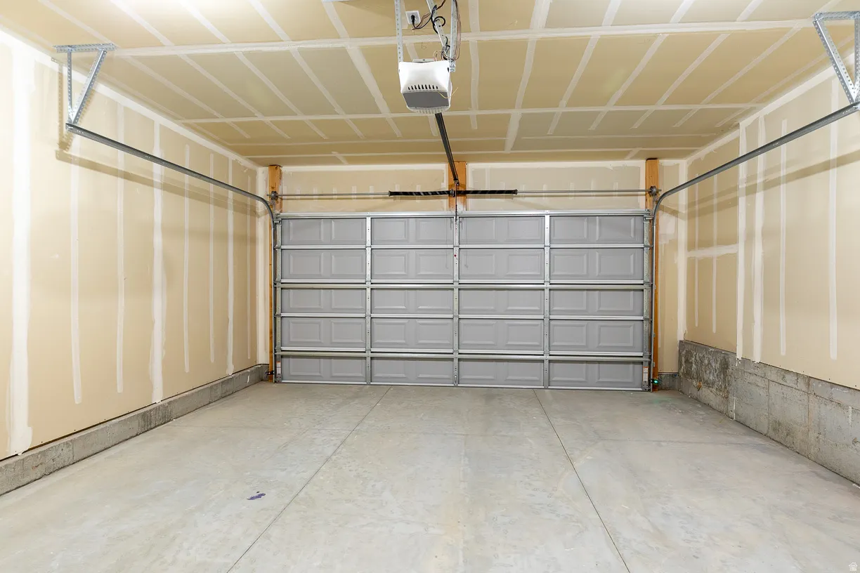 Spacious two car garage with concrete flooring featuring a panel-style garage door and an automatic opener system