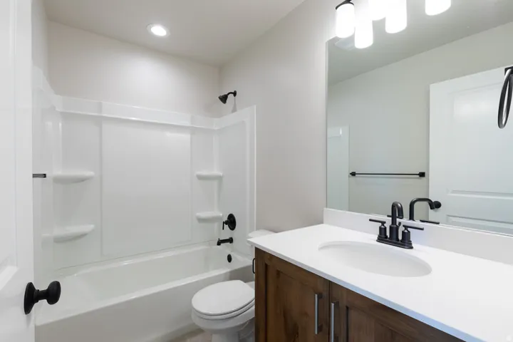 Upstairs common bathroom featuring a wood-finish vanity with a white countertop and undermount sink