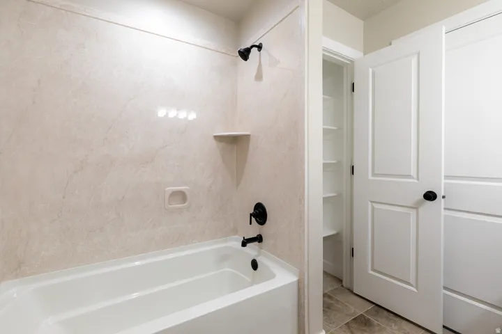 Primary bedroom bathroom has a white soaking tub featuring a black showerhead, black tub faucet, and a wall-mounted soap dish