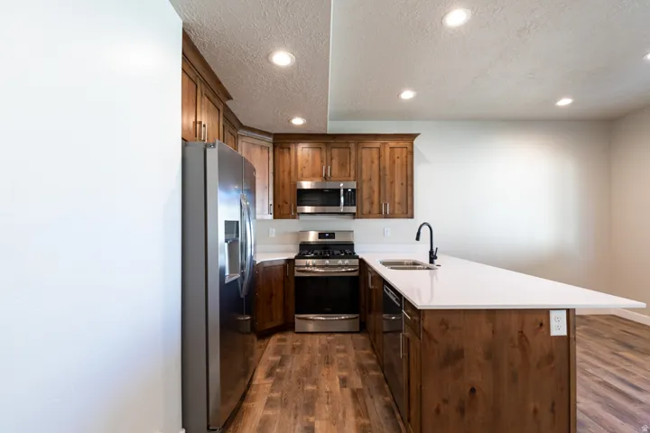 Kitchen featuring wood-finish cabinetry, stainless steel appliances, white countertops, and wood-finish flooring