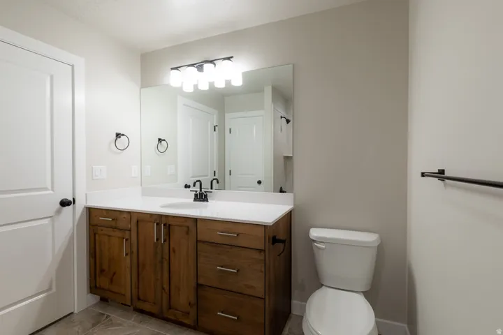 Primary bedroom bathroom vanity featuring a light-toned countertop, integrated sink, and wood-finish cabinetry