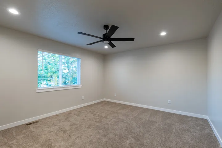 Carpeted room featuring a ceiling fan, recessed lighting, and a window with blinds