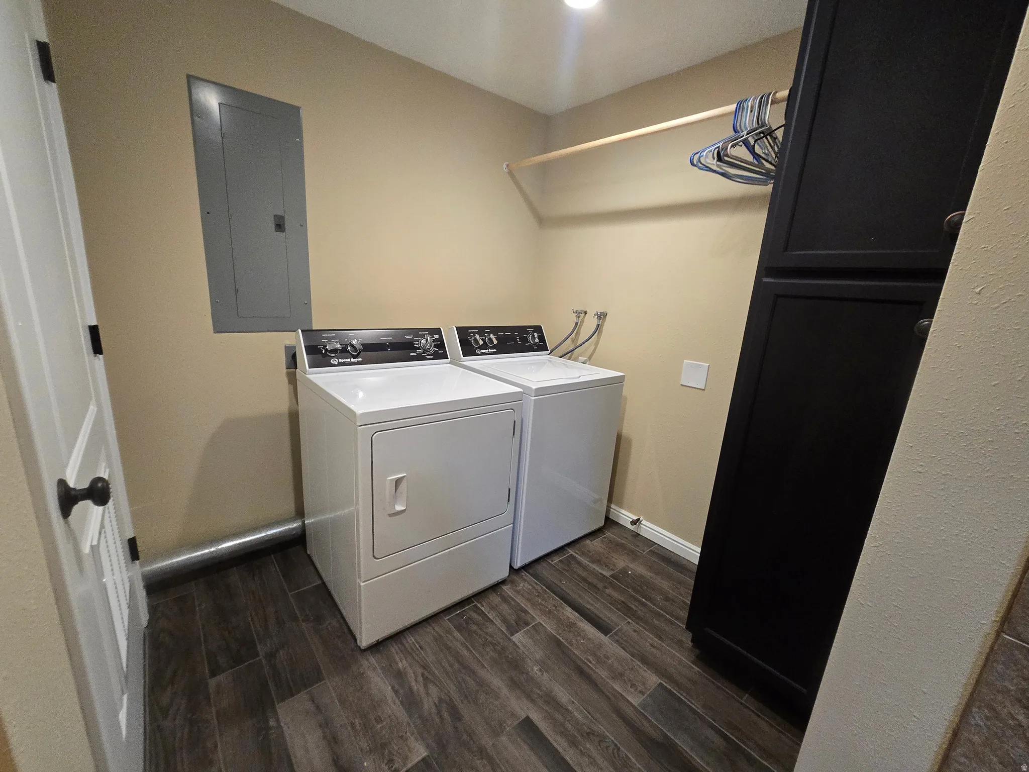 Dedicated laundry area featuring wood-finish flooring, a built-in hanging rod, recessed lighting, and integrated dark cabinetry