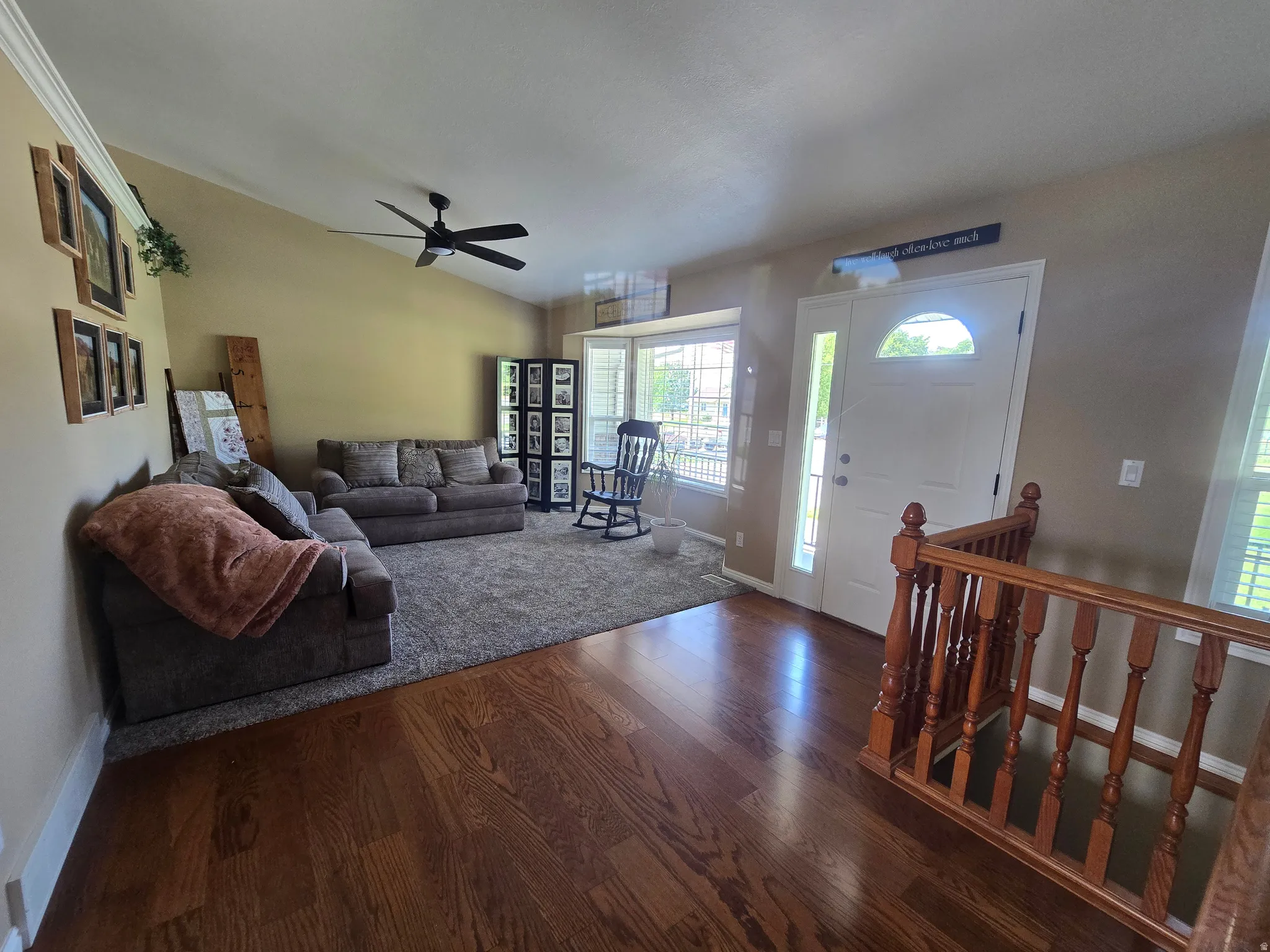 Entryway featuring rich wood-finish flooring, a white paneled front door with an arched transom window, and a wood baluster railing