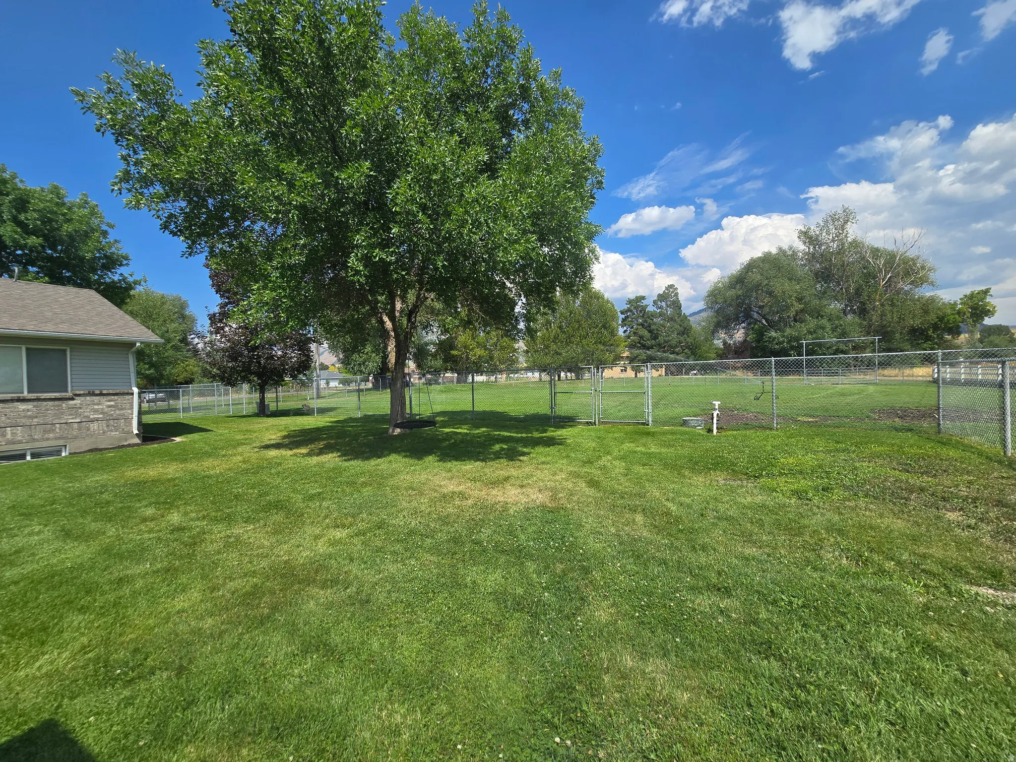 Expansive green lawn featuring mature trees providing ample shade