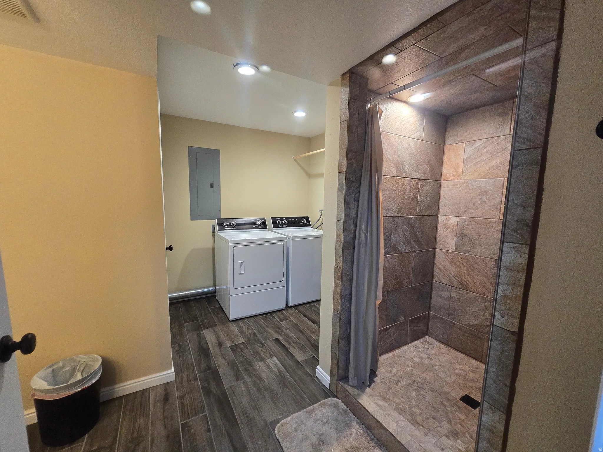Tiled shower enclosure featuring recessed lighting and a stone-look floor