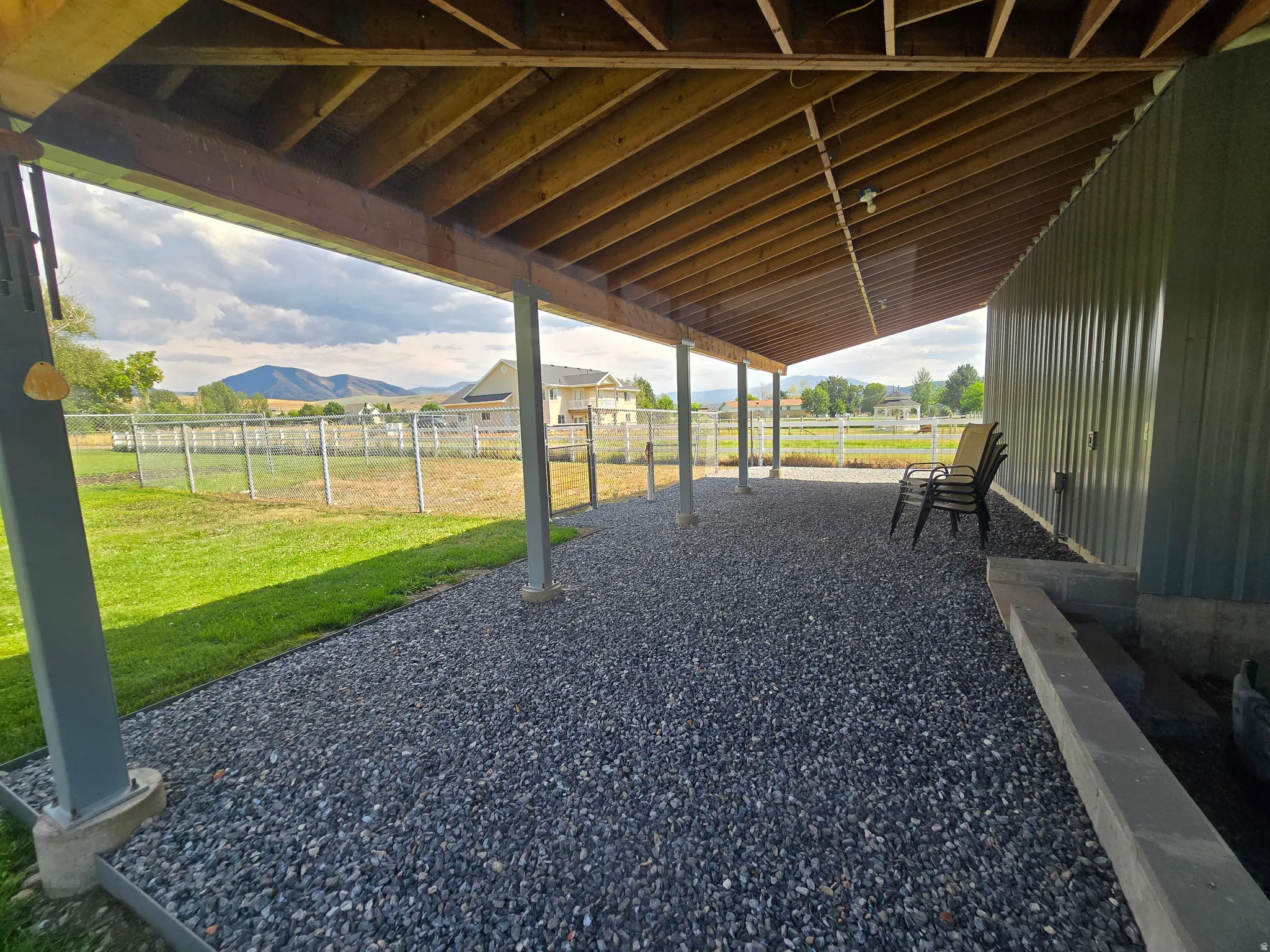 Covered patio with exposed wood ceiling beams, supported by metal posts