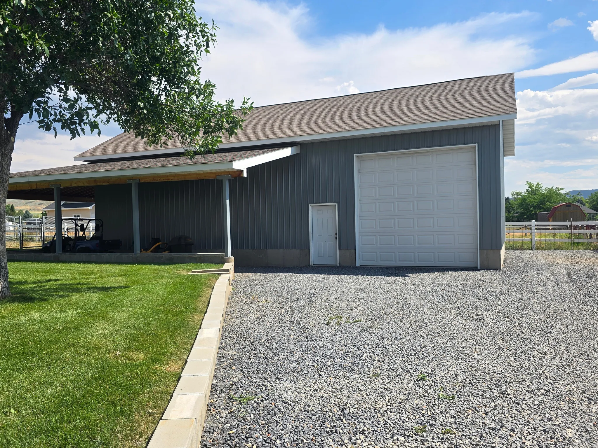 Steel-sided ancillary structure featuring a pitched roof and a gravel driveway