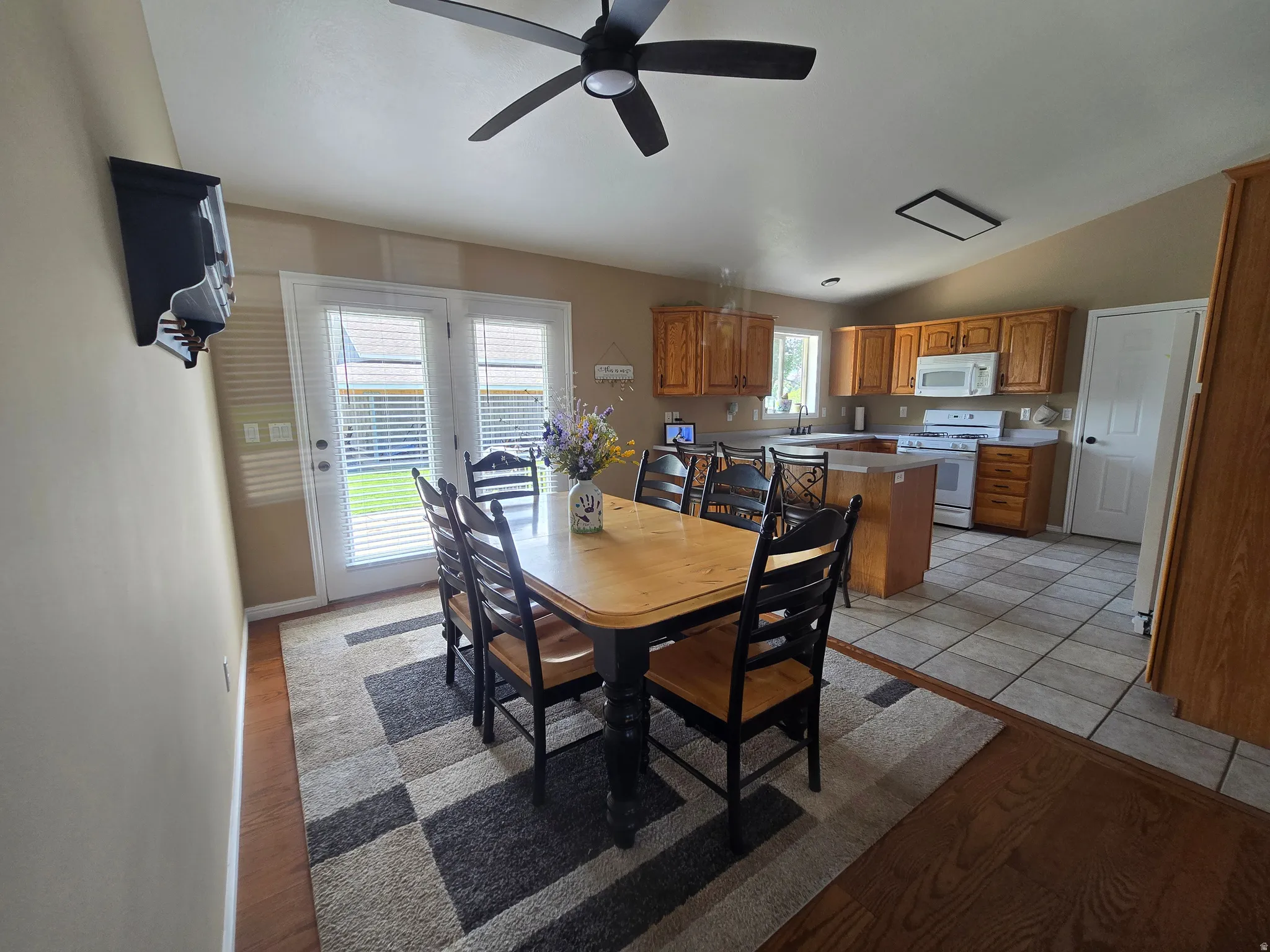 Kitchen and dining area featuring warm wood-finish cabinetry, white appliances, and a central island