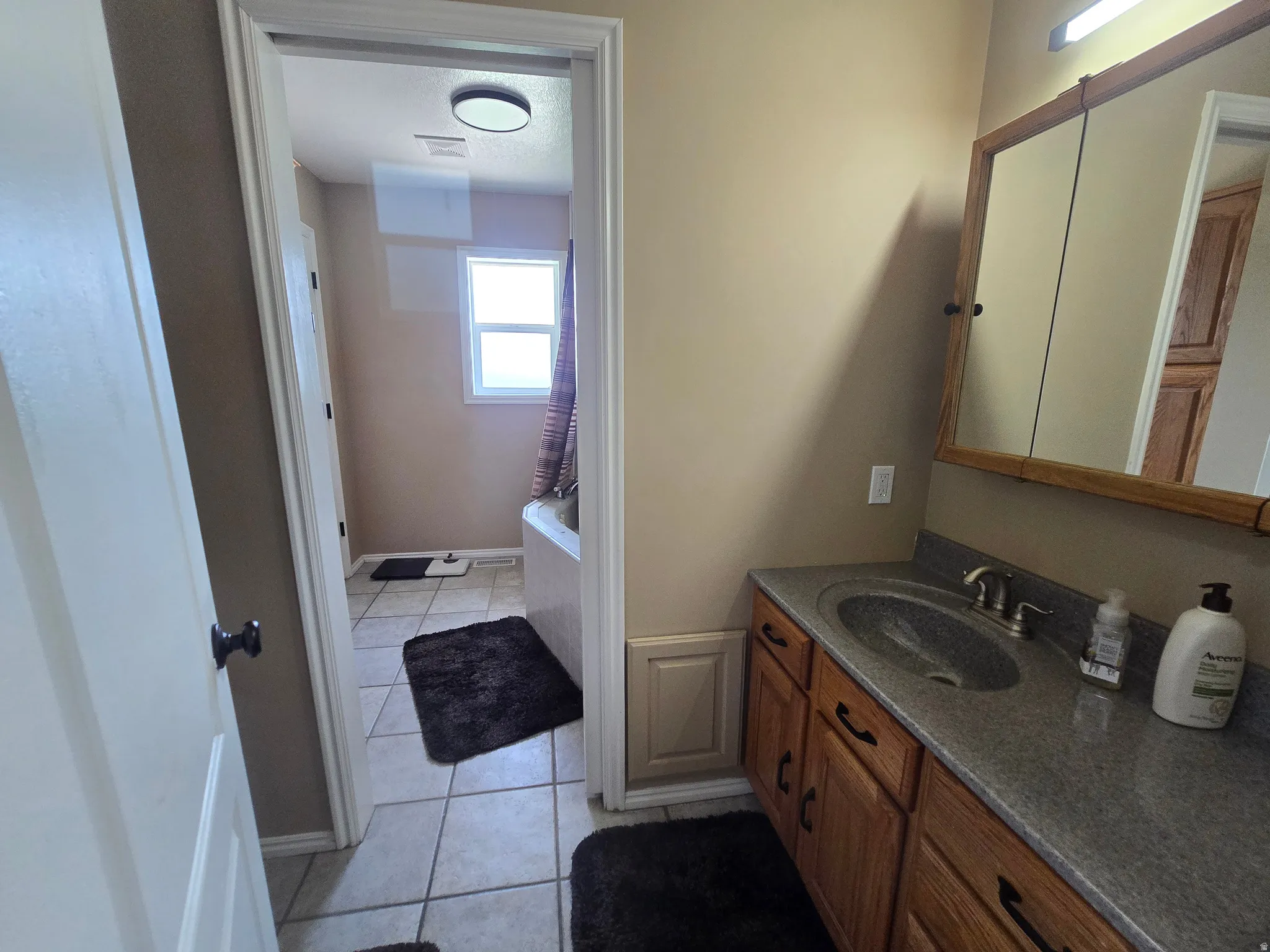 Bathroom vanity featuring a dark gray countertop with an integrated sink and brushed nickel faucet